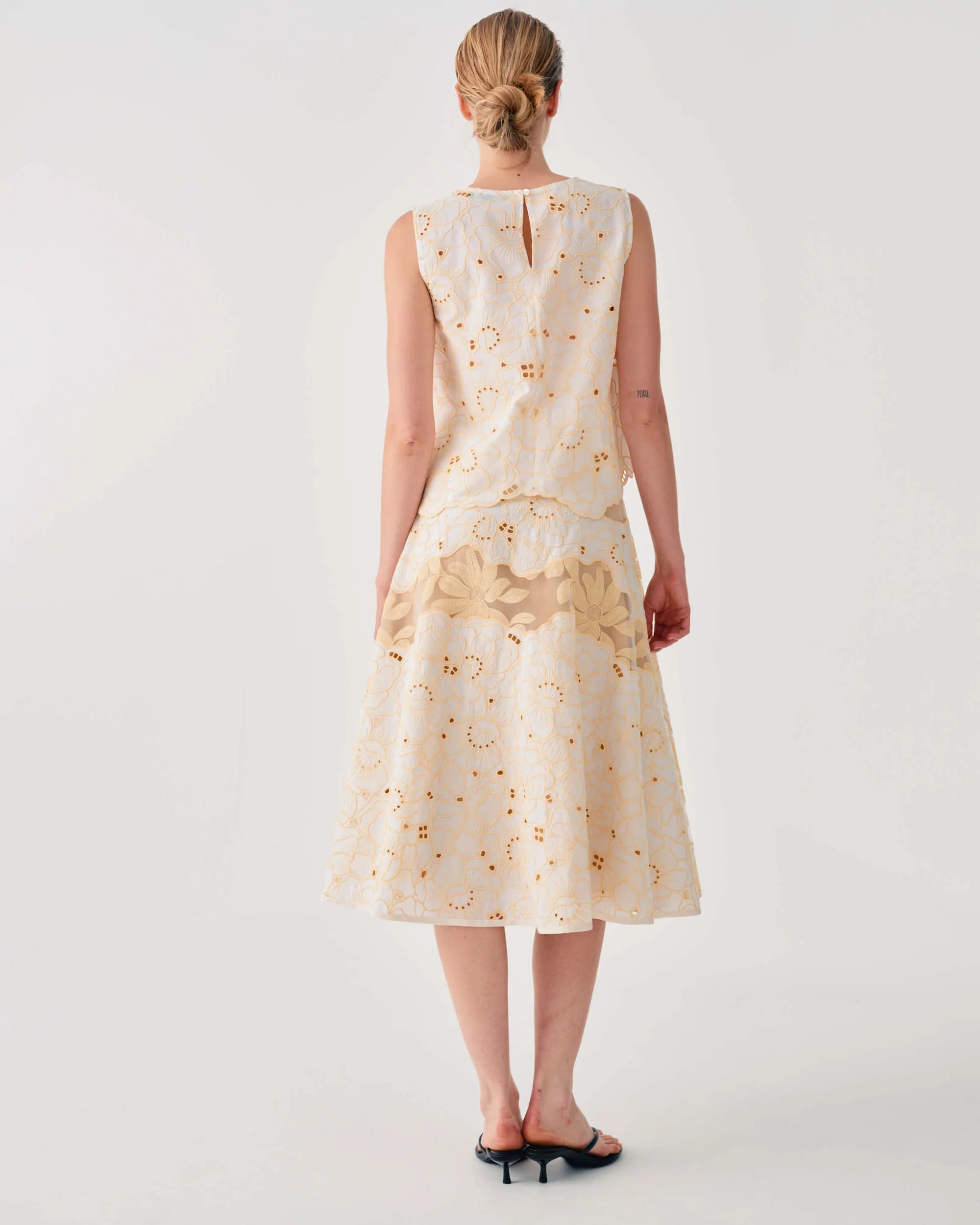 Woman wearing a cream-colored dress with floral pattern on a white background