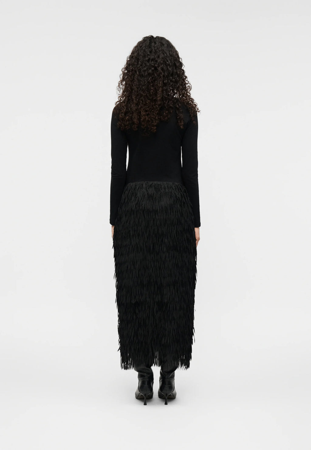 Person wearing a black top with a feathered like Sabrina skirt on a white background