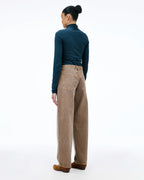 A model shown from the back wearing a dark teal long-sleeve mock neck top, beige wide-leg corduroy pants, and brown suede shoes, against a solid white studio background.