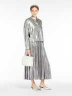 Woman wearing a silver metallic outfit with a white handbag on a white background