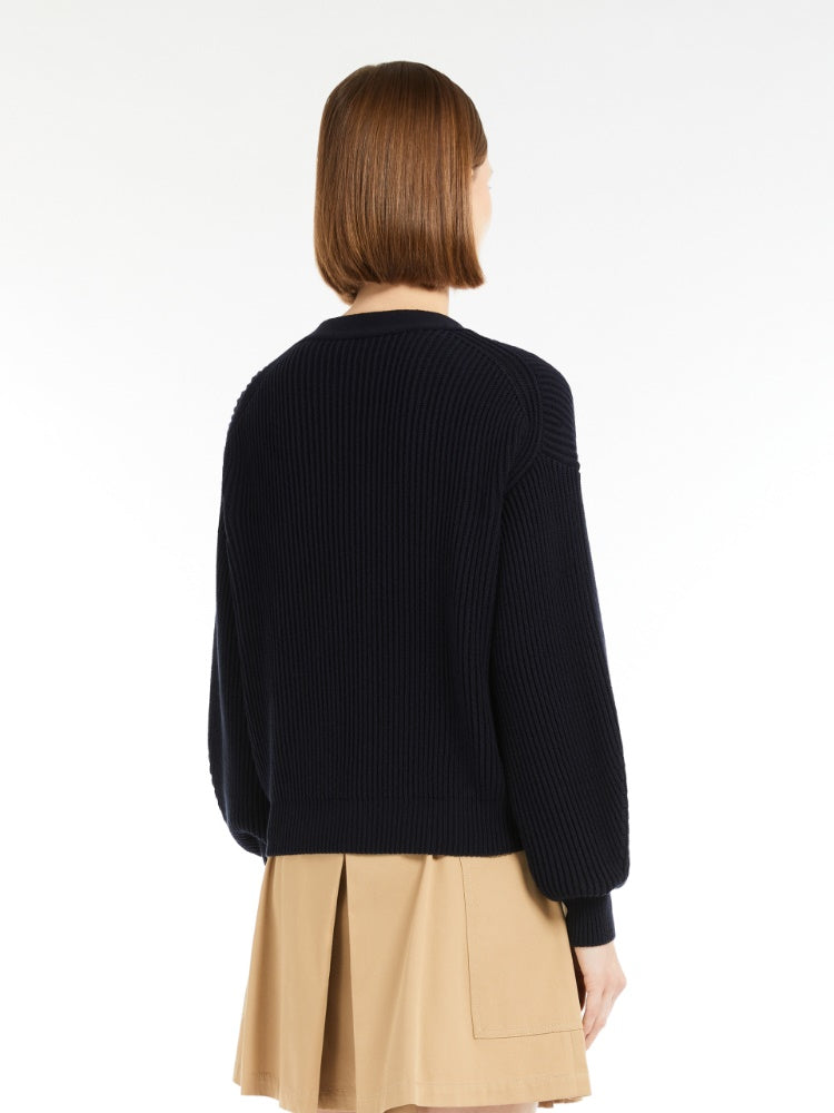 Person wearing a navy sweater and beige skirt on a white background