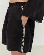 Black shorts with geometric side panels on a plain background