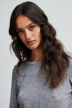 Woman wearing a gray sweater against a plain background