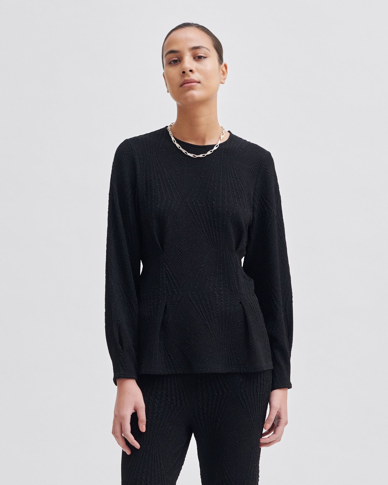 Person wearing a black long-sleeve top on a white background