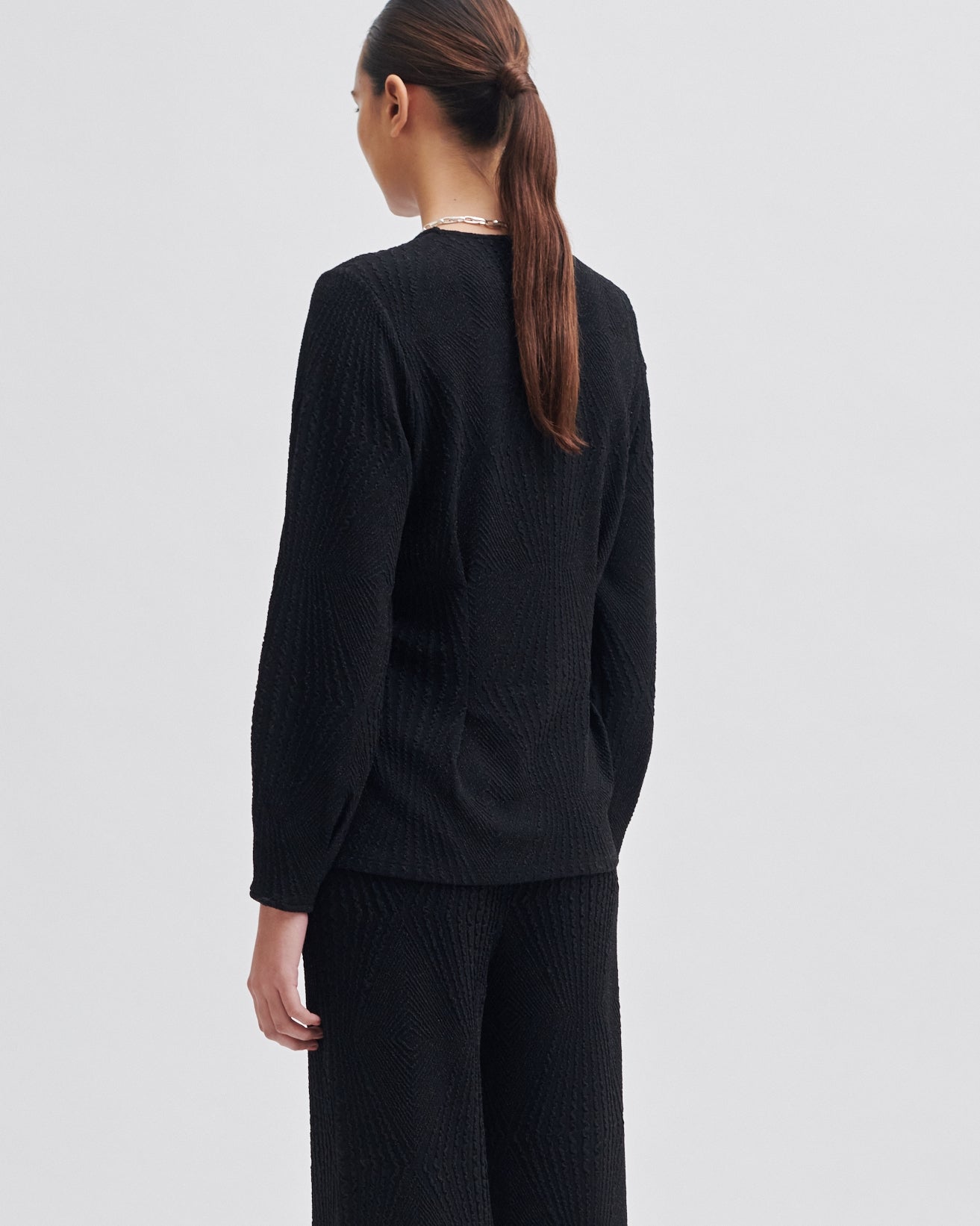 Person wearing a black outfit on a light gray background