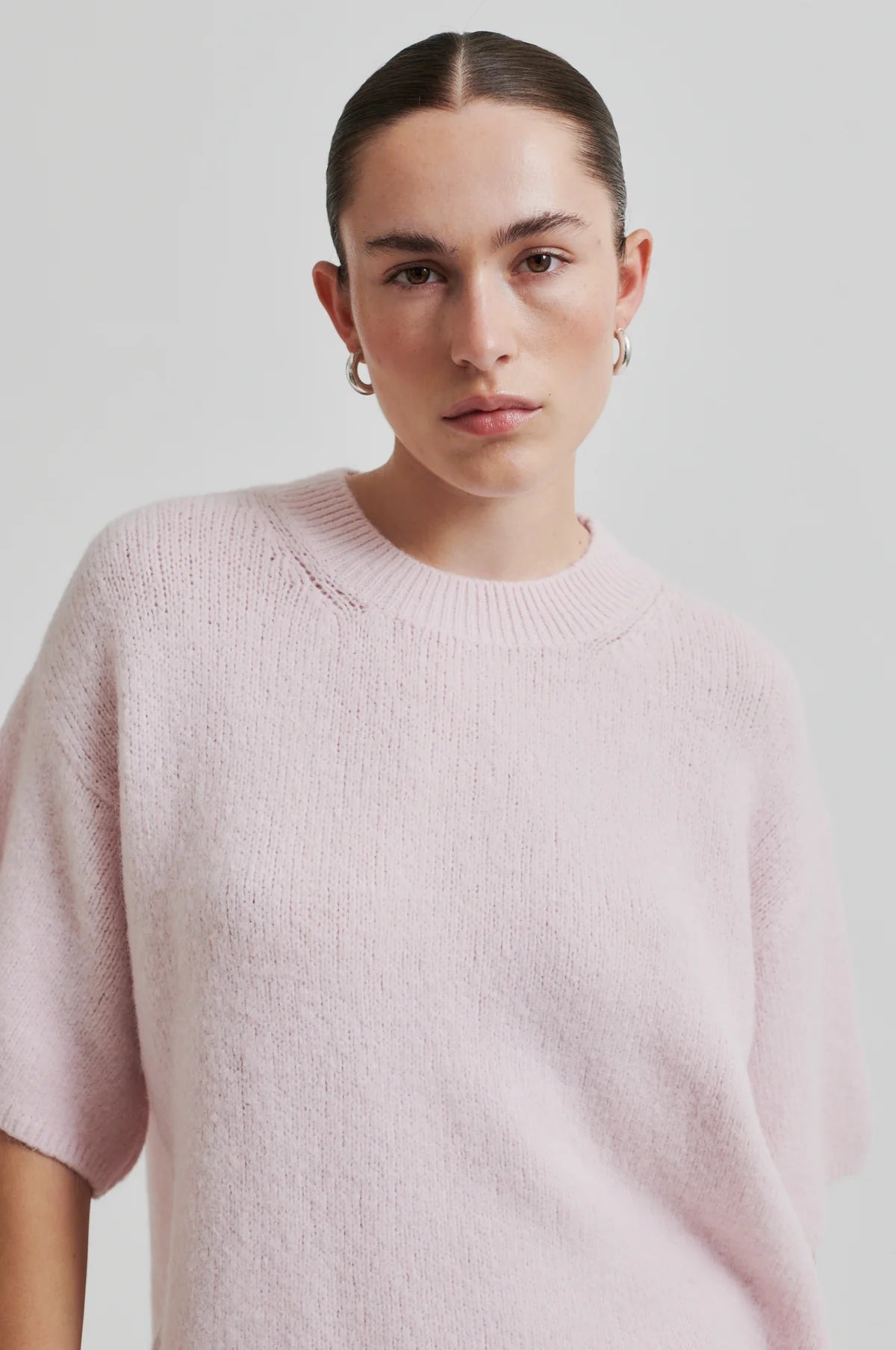 Person wearing a light pink  second female sweater against a plain background.shop online