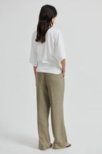 Person wearing a white shirt and beige pants on a light gray background