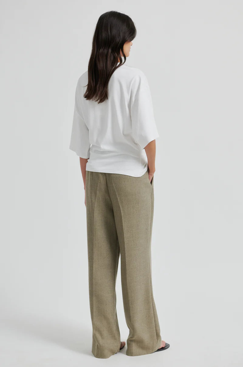 Person wearing a white shirt and beige pants on a light gray background