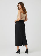 Woman wearing a beige top and black wide-leg pants on a white background