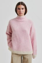 Person wearing a pink textured sweater on a white background