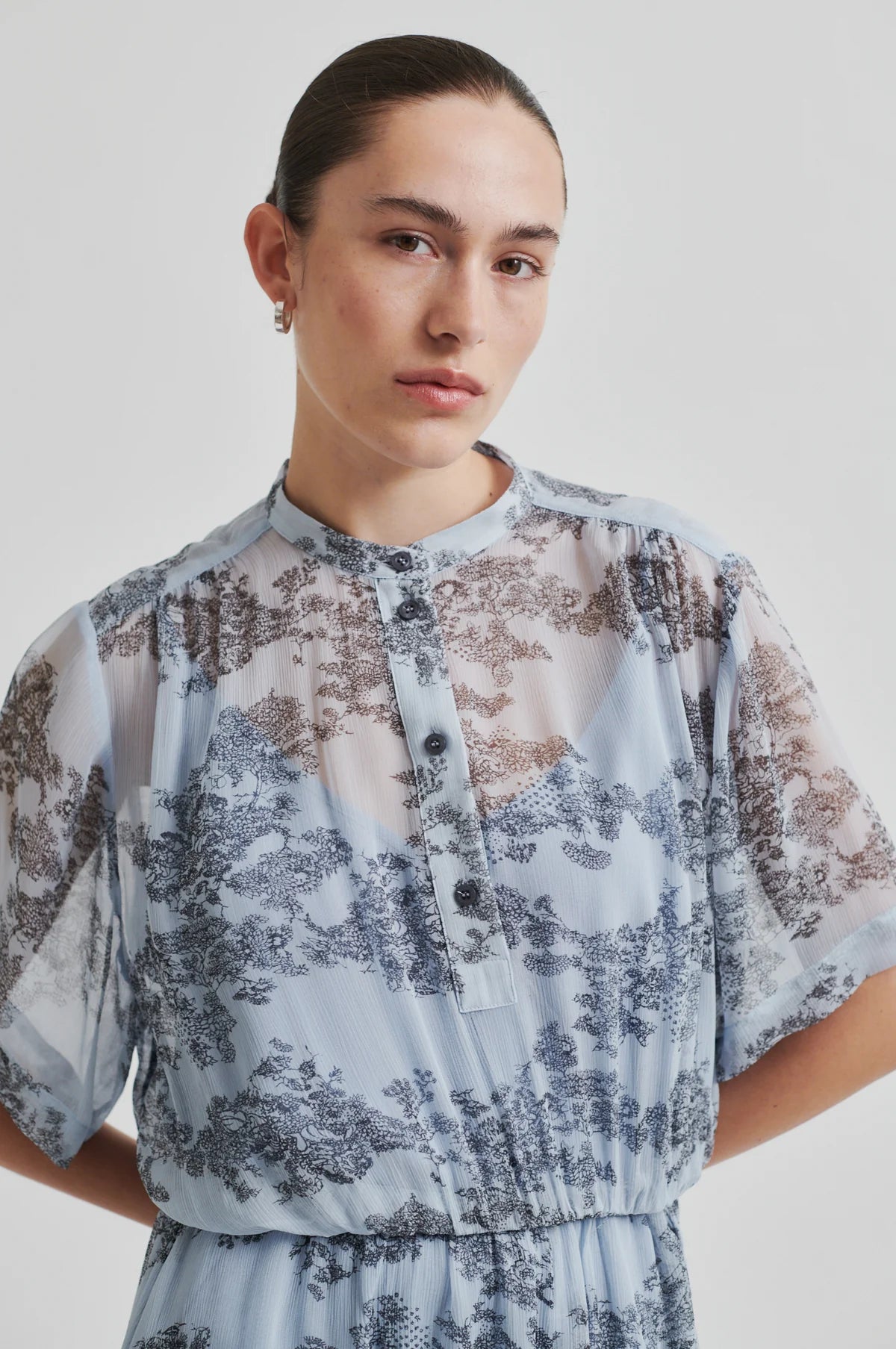 Woman wearing a second female light blue floral dress against a plain background.shop online