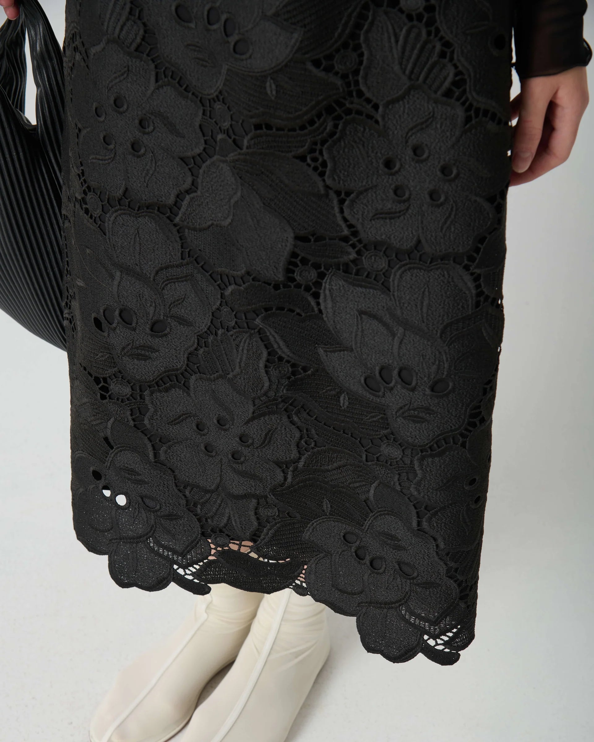 Black lace skirt worn by a person on a white background