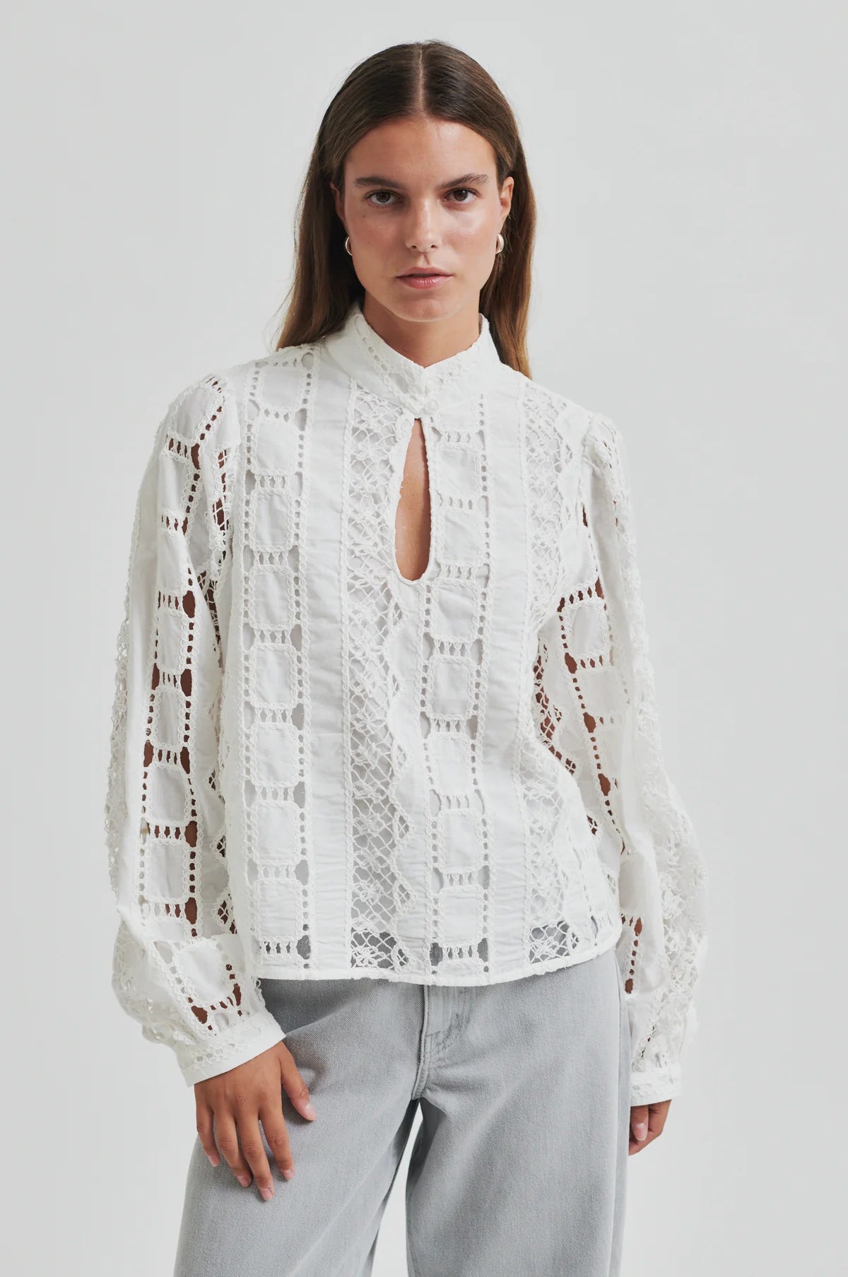 Woman wearing a white lace blouse against a plain background