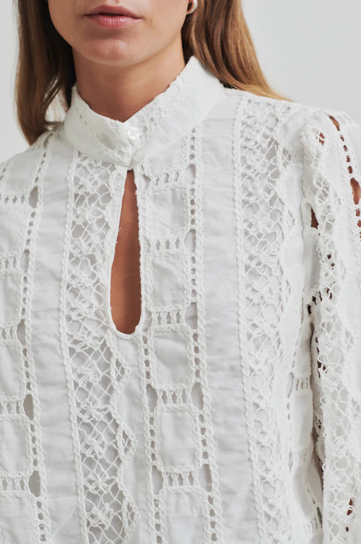 White lace blouse worn by a person on a white background