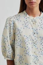 Close-up of a person wearing a floral blouse with a neutral background
