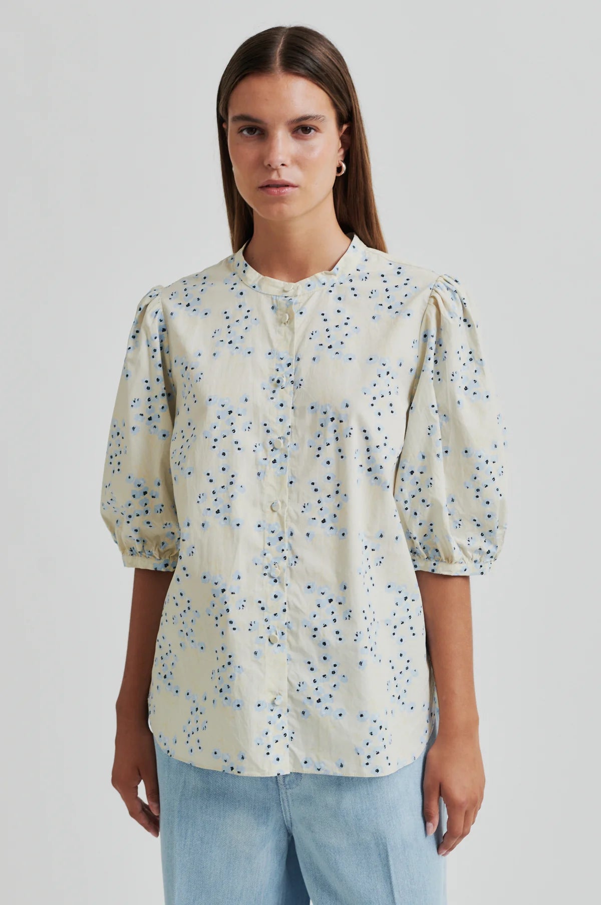 Woman wearing a floral blouse with puffed sleeves on a plain background