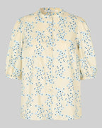 Beige blouse with blue floral pattern on a gray background