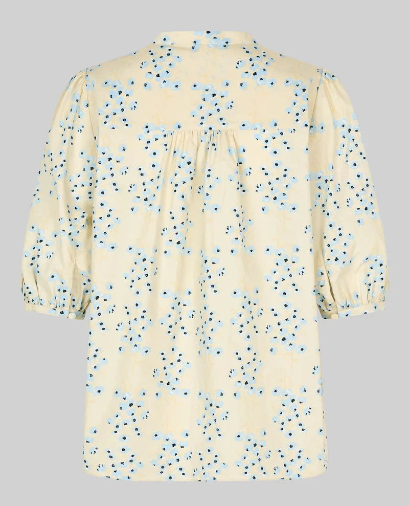 Beige blouse with blue floral pattern on a gray background