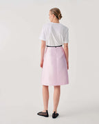Person wearing a white shirt and pink skirt on a plain background