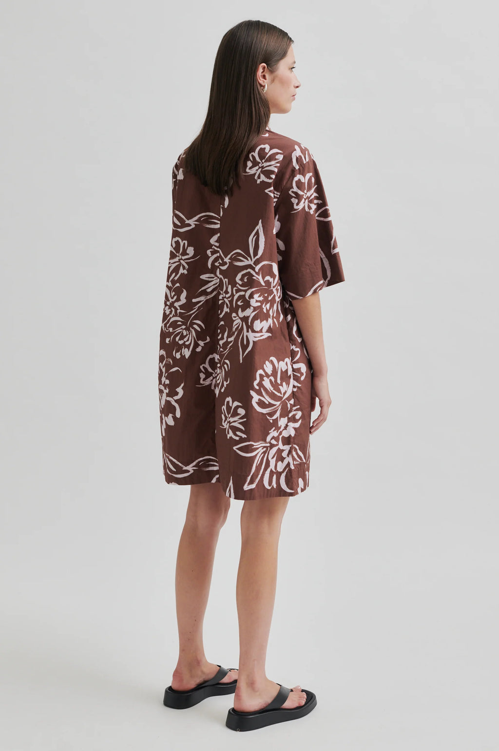 Woman wearing a brown floral dress on a white background