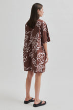 Woman wearing a brown floral dress on a white background