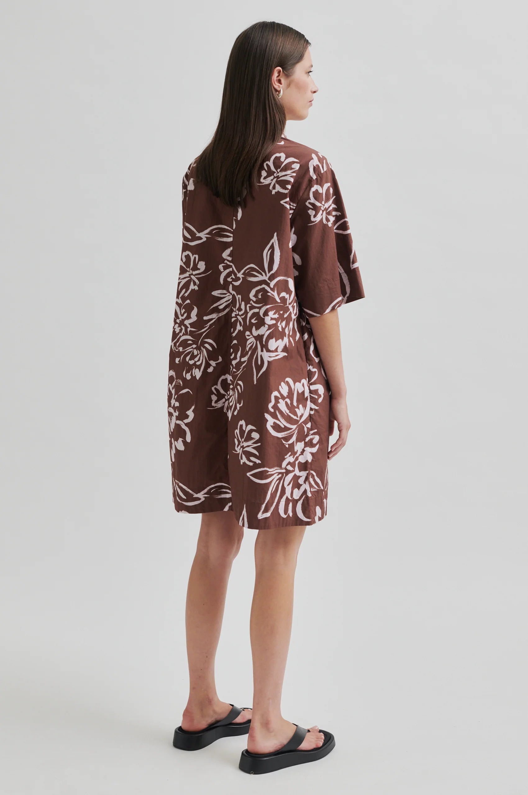 Woman wearing a brown floral dress on a white background
