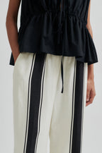 Black top and white pants with black stripes on a white background