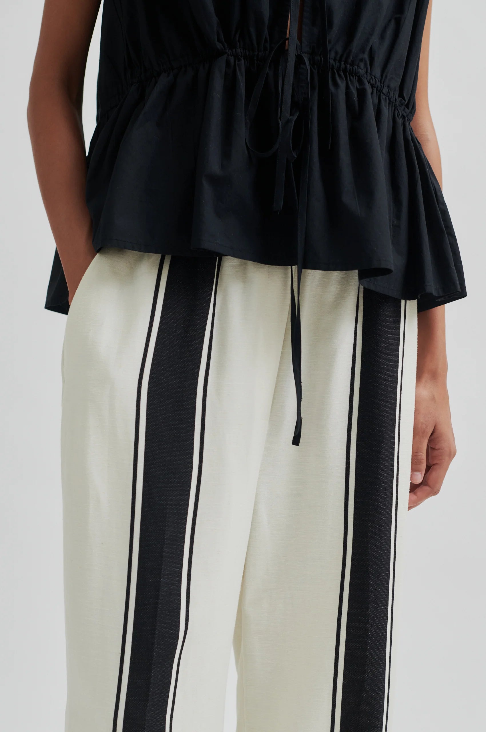 Black top and white pants with black stripes on a white background