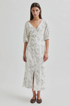 Woman wearing a white floral dress on a light gray background