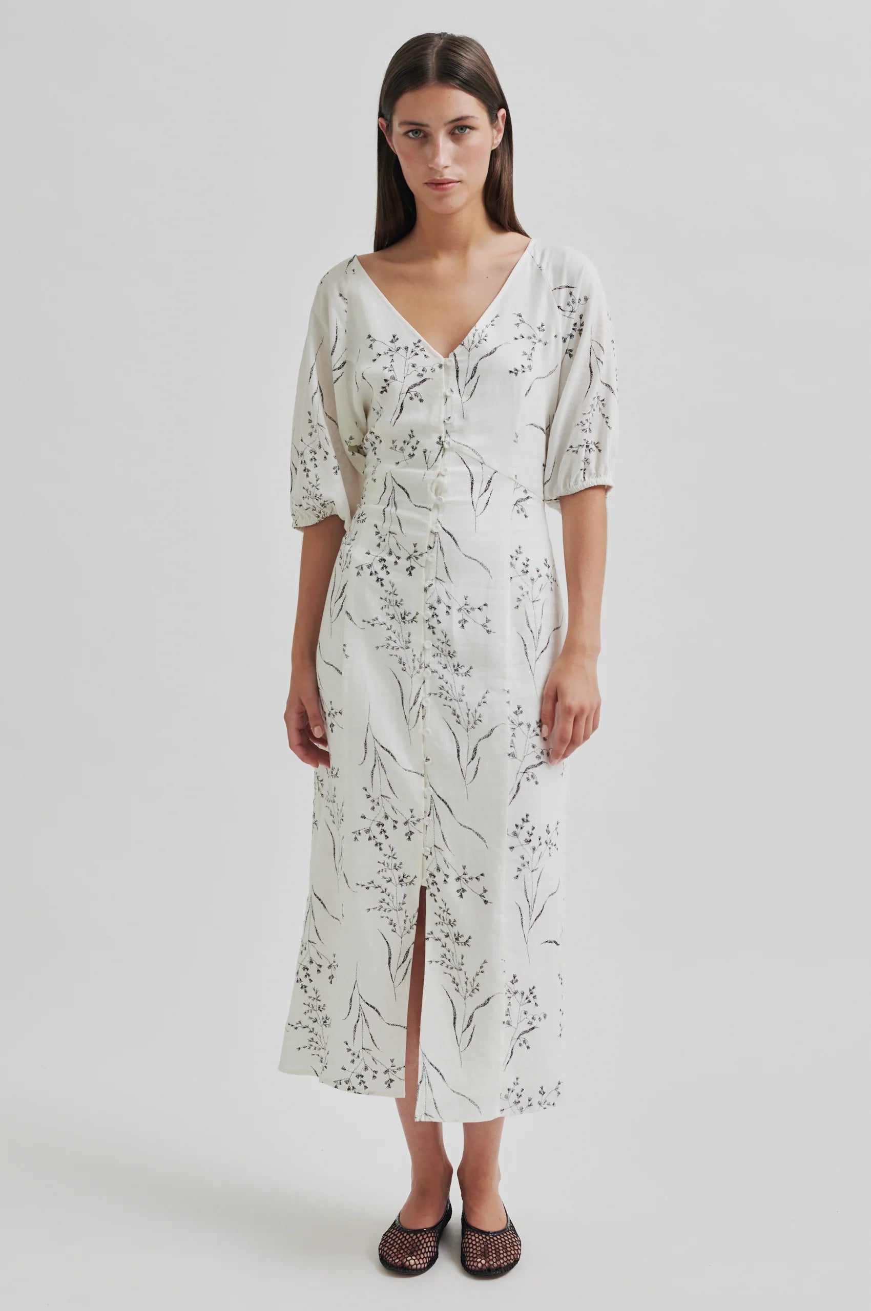 Woman wearing a white floral dress on a light gray background