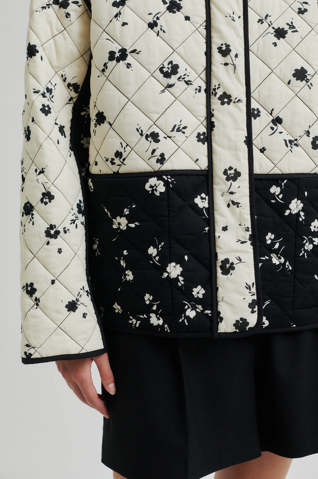 Quilted jacket with black floral pattern on a white background