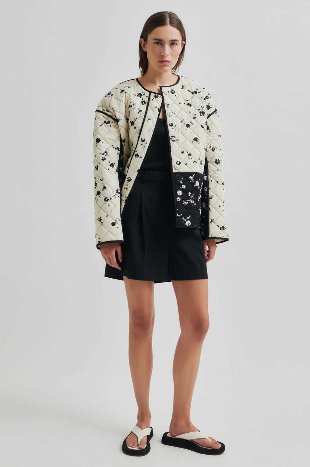 Woman wearing a floral jacket and black skirt on a white background