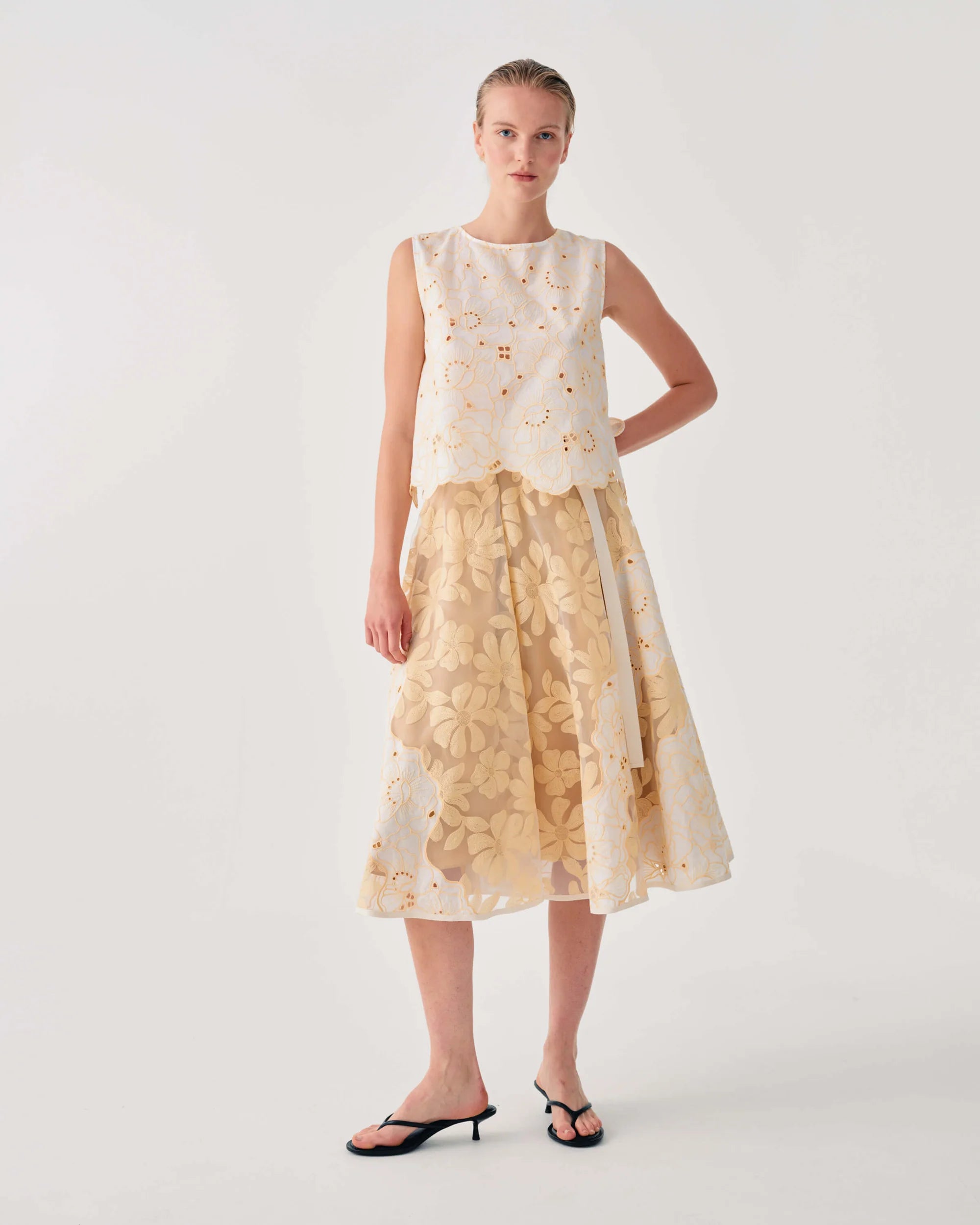 Woman wearing a sleeveless top and floral skirt on a white background