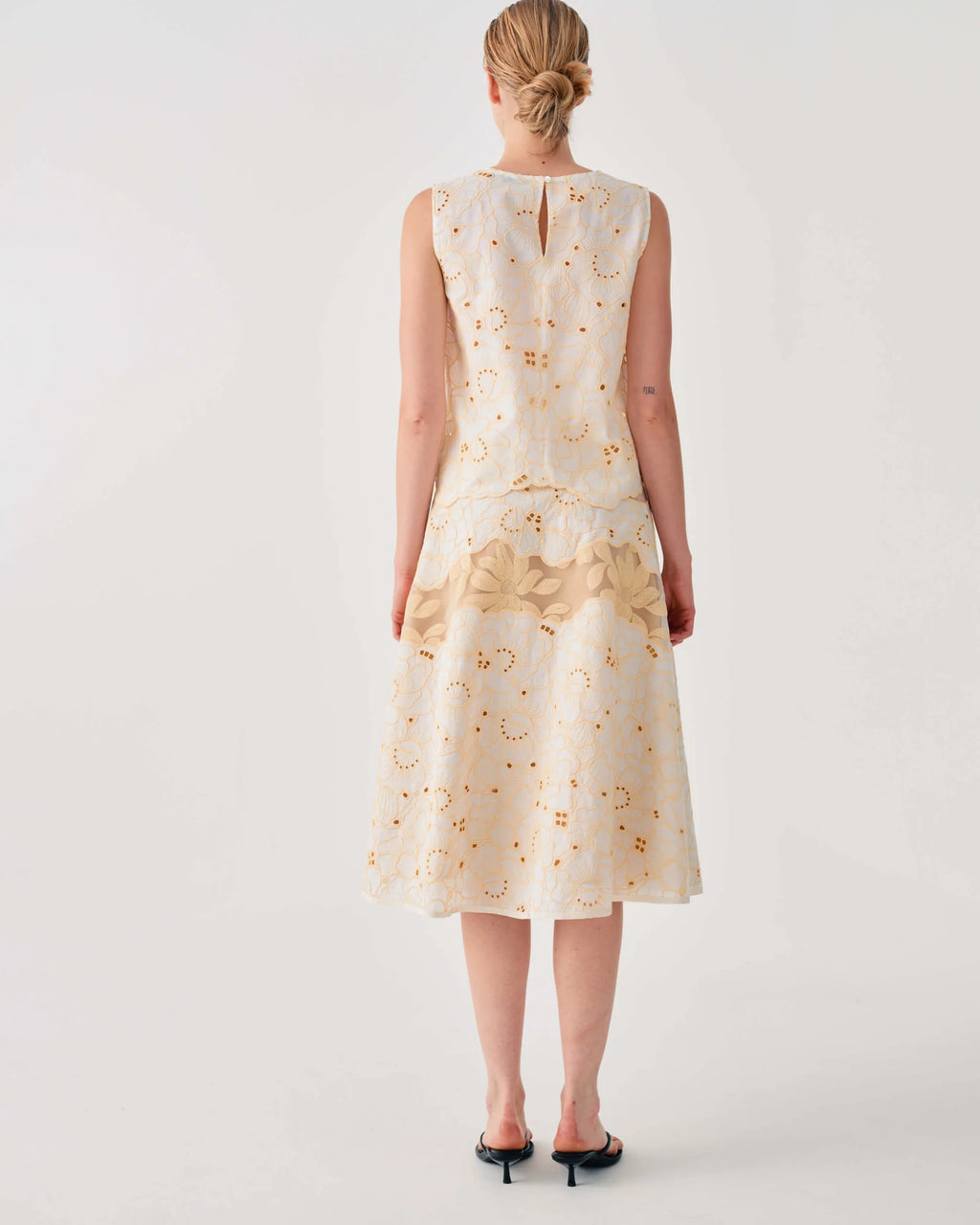 Woman wearing a cream-colored dress with floral pattern on a white background