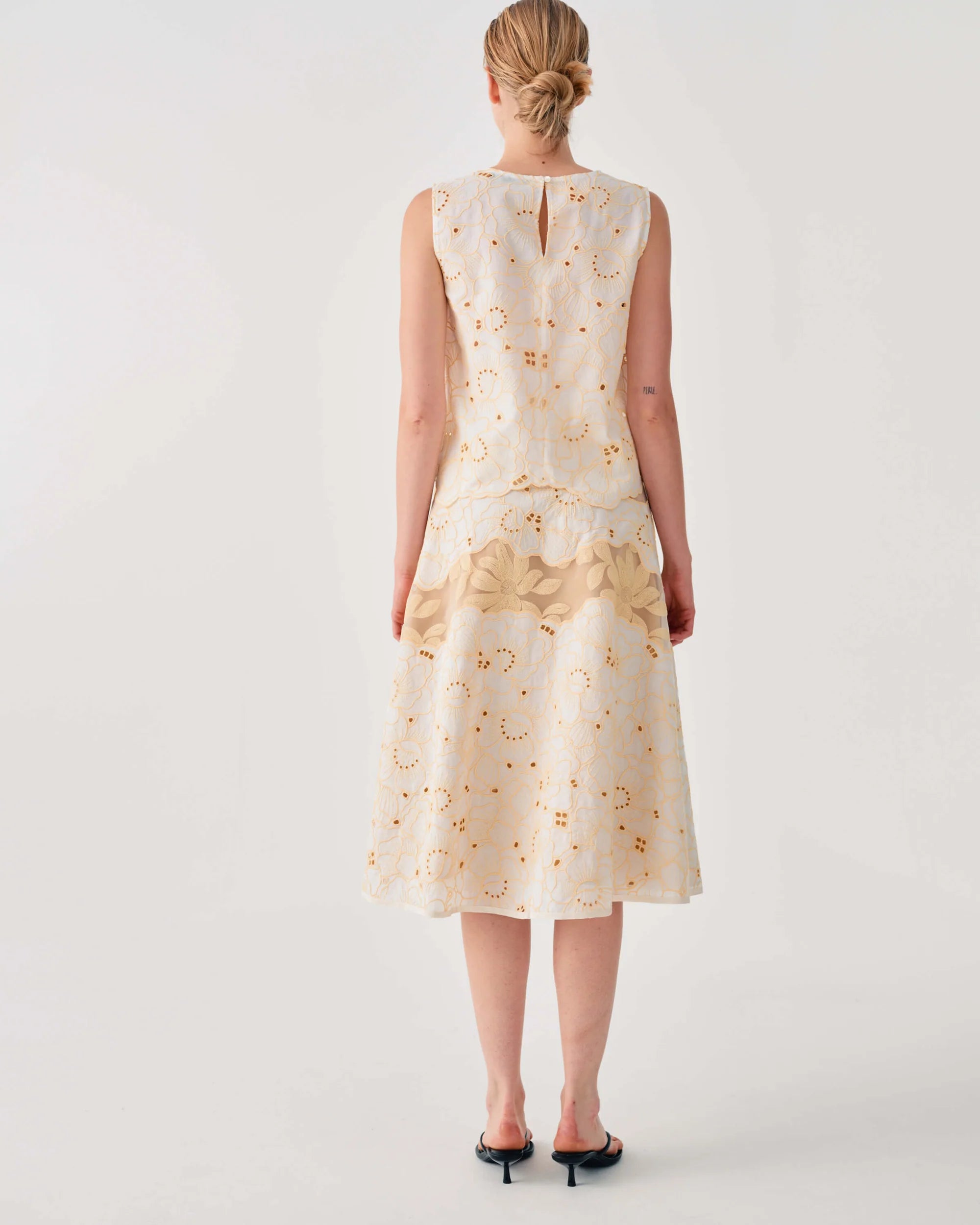 Woman wearing a cream-colored dress with floral pattern on a white background