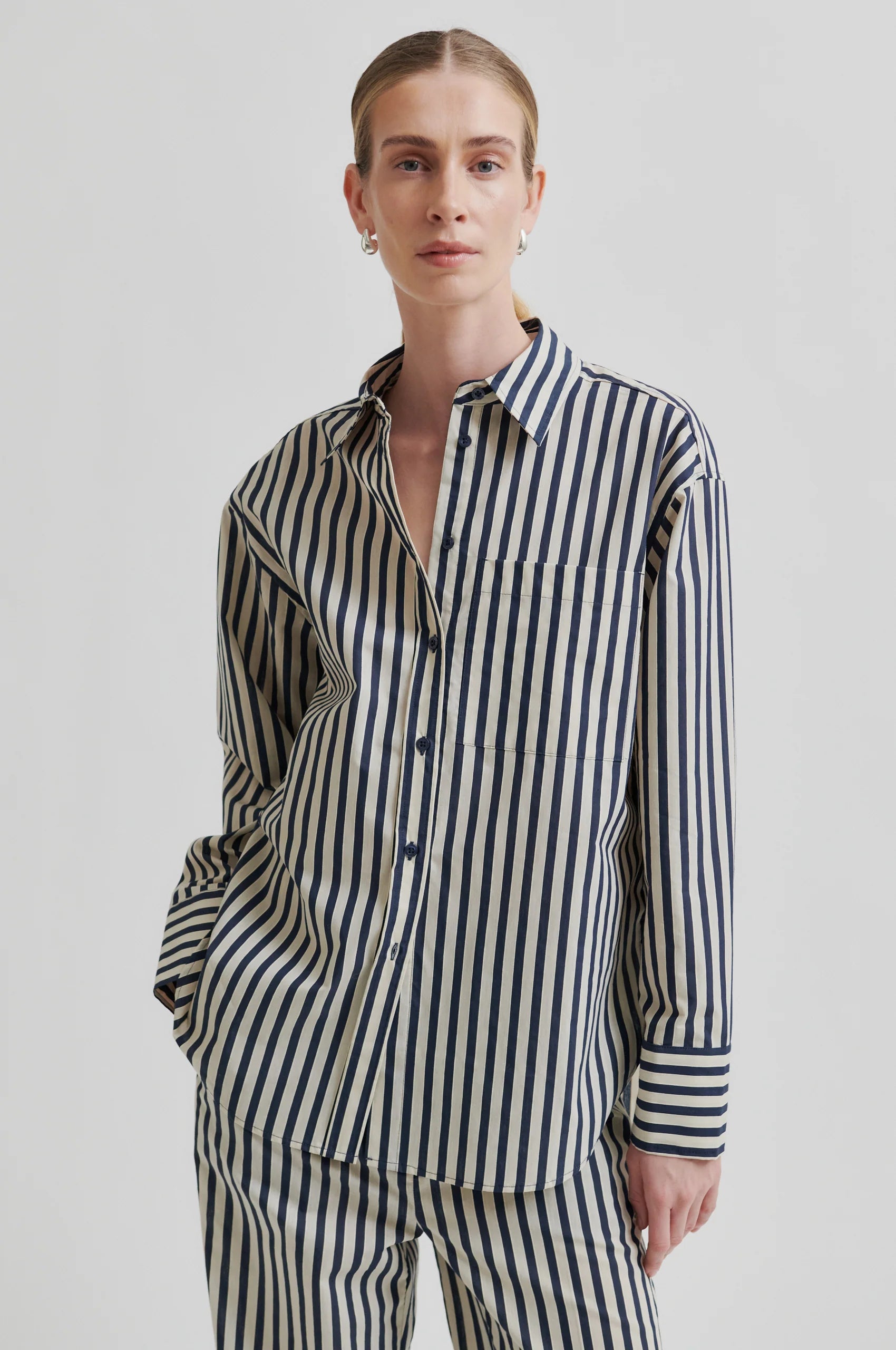 Person wearing a black and white striped shirt and pants on a plain background