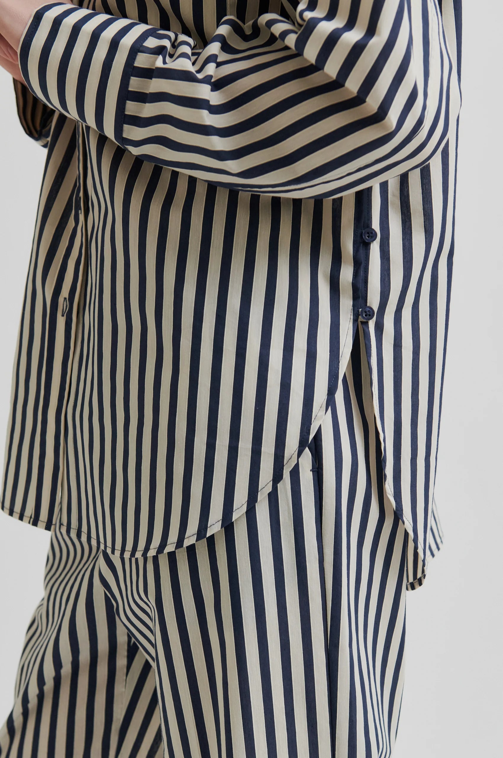 Navy and beige striped shirt and pants on a plain background