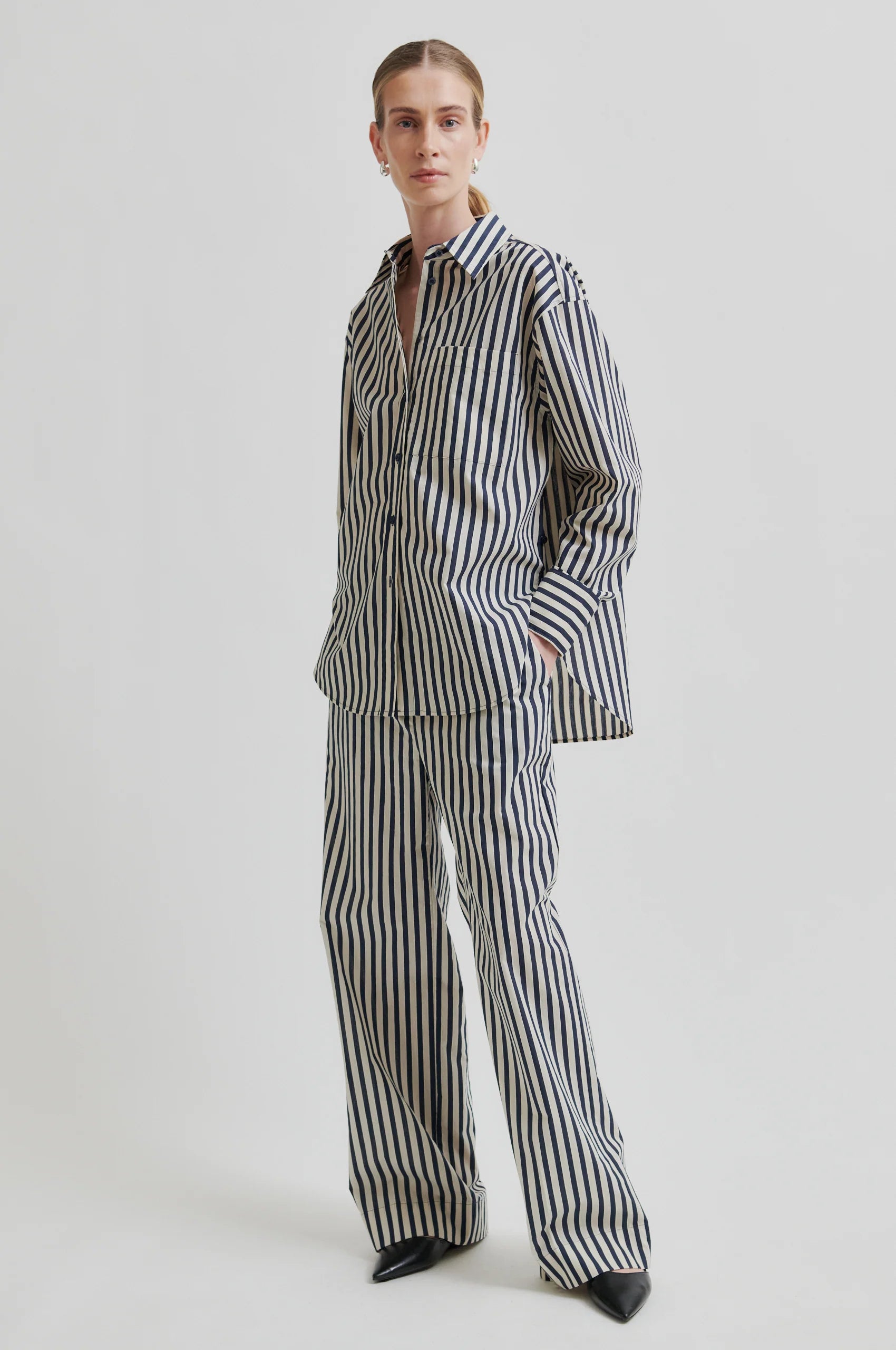 Person wearing a black and white striped outfit on a light gray background