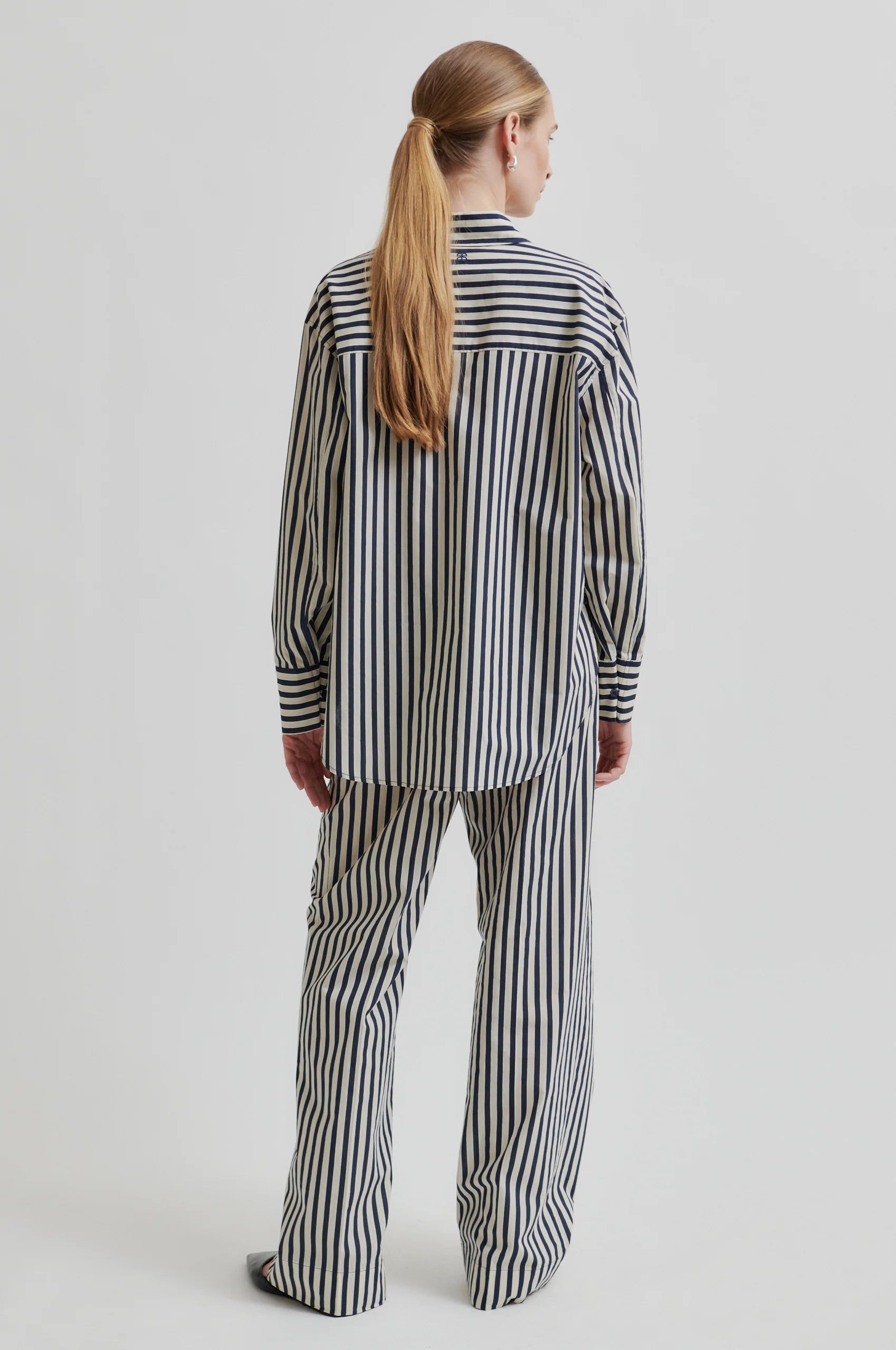 Person wearing a black and white striped outfit on a plain background