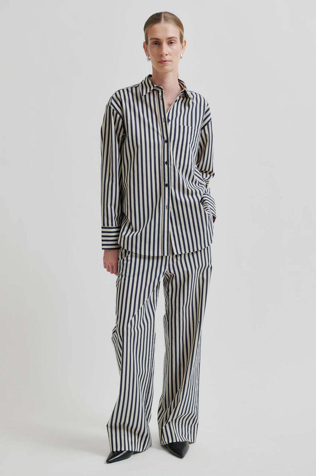 Person wearing a black and white striped pajama set on a white background