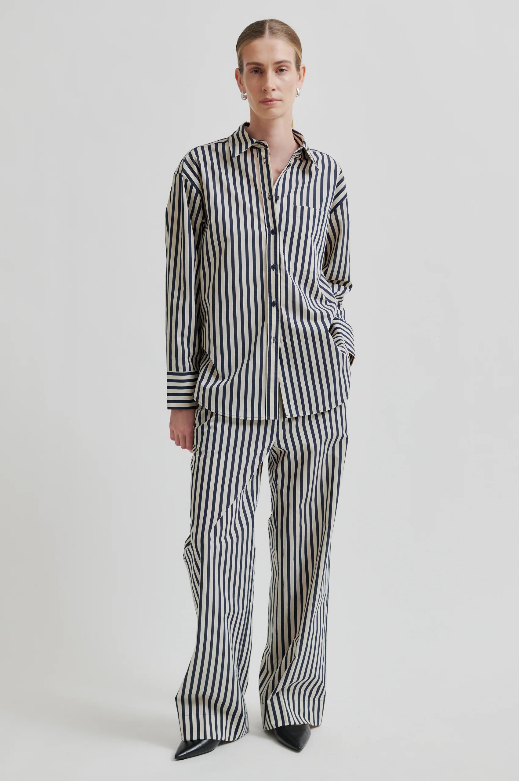 Person wearing a black and white striped pajama set on a white background
