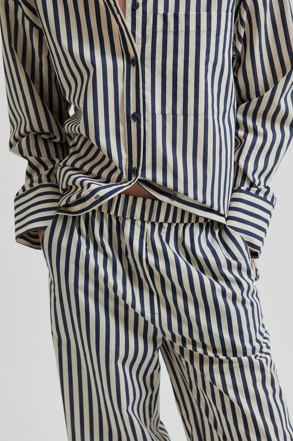 Person wearing a striped shirt and pants on a white background