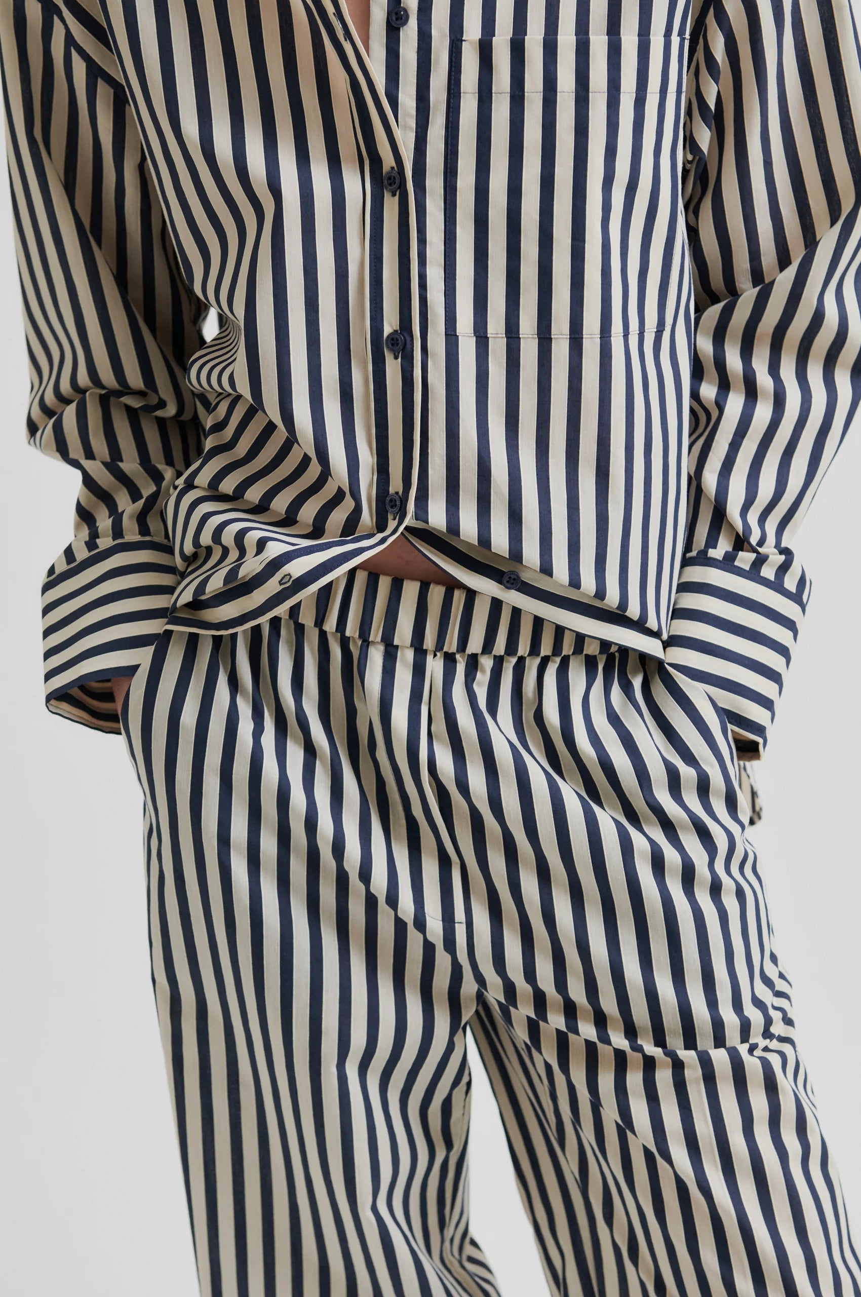 Person wearing a striped shirt and pants on a white background