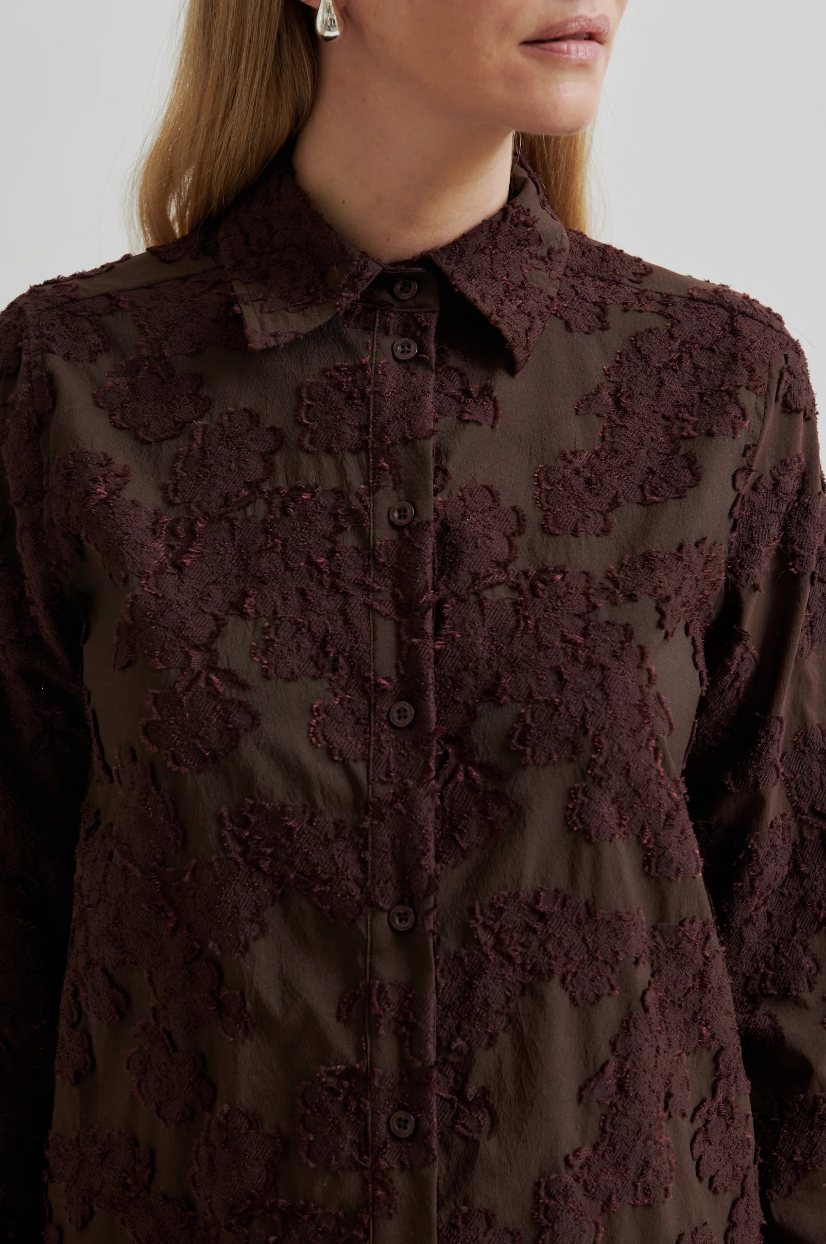 Brown lace blouse worn by a person on a white background