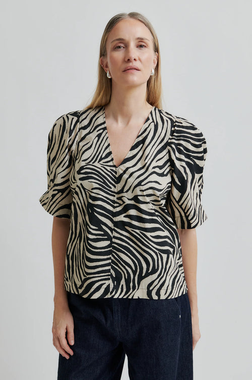 Woman wearing a zebra print top against a plain background
