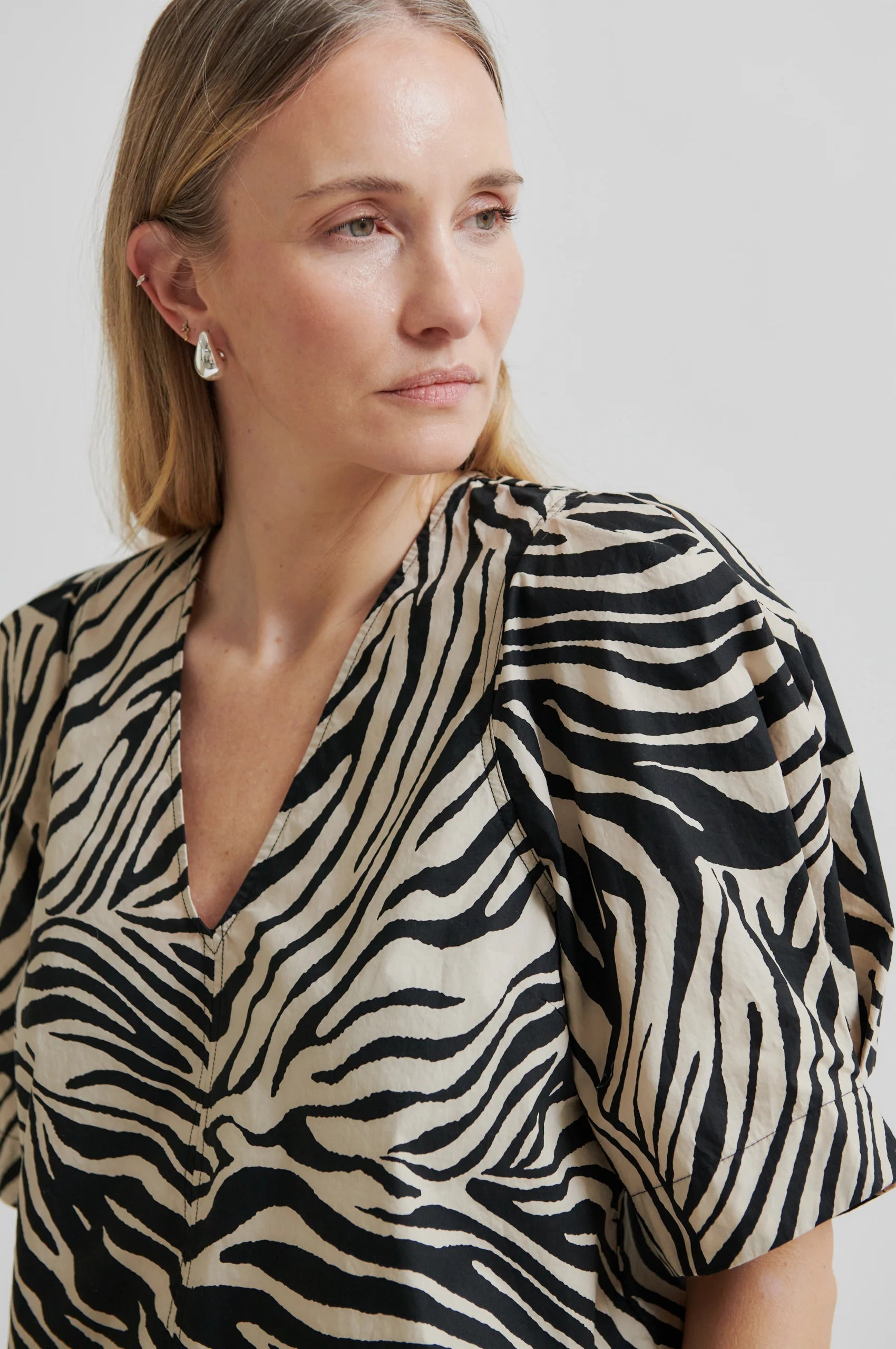 Woman wearing a zebra print dress against a plain background