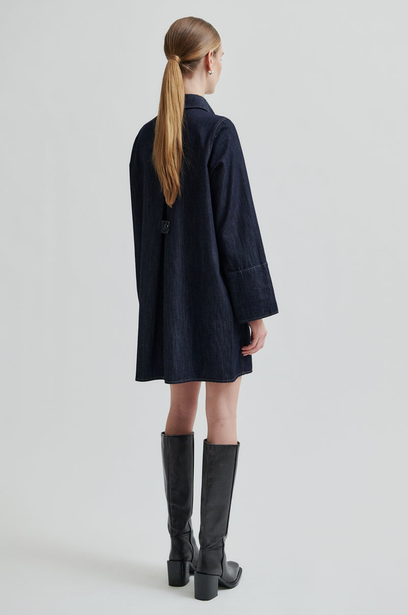 Person wearing a dark coat and black knee-high boots on a light gray background