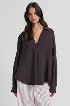 Woman wearing a dark brown blouse with a plain background