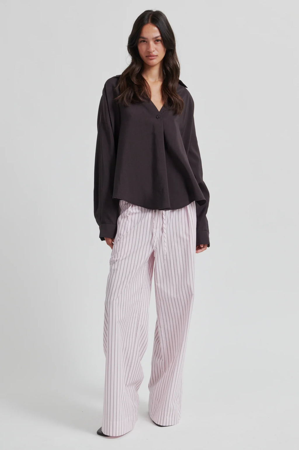 Woman wearing a dark blouse and striped pants on a white background