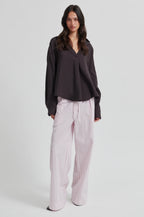 Woman wearing a dark blouse and striped pants on a white background